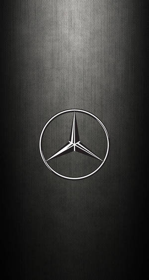 Mercedes-Benz 標誌在深色紋理背景上帶有光線。