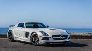 白色Mercedes SLS AMG跑車在日落時停泊在海邊。