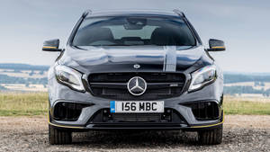 銀色 Mercedes-AMG A45 S 停泊在碎石路上，以山丘為背景。