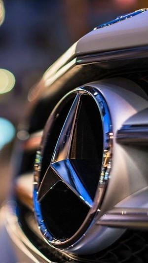 夜間車上閃亮的 Mercedes-Benz 標誌與散景燈光。