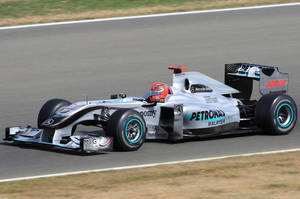 銀色和藍綠色的 Formula 1 賽車在賽道上飛馳，車手戴著紅色頭盔。 — 平治 AMG 壁紙