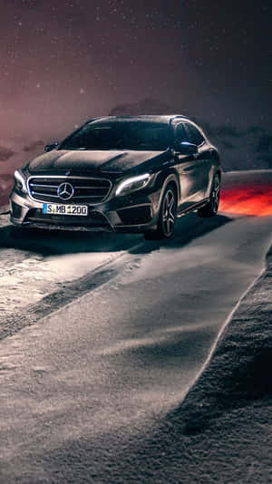黑色Mercedes SUV在夜間雪路上行駛，車頭燈閃亮，排氣管噴出火橙色廢氣。