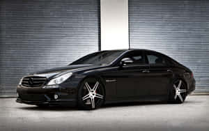 黑色Mercedes-Benz CLS63 AMG配銀色輪圈，停在金屬車庫門前。