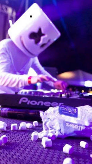DJ Marshmello 喺紫色燈光同枱上嘅棉花糖下表演緊。