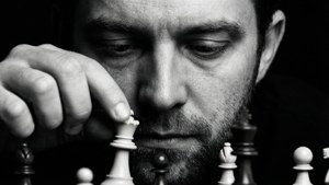 男子全神貫注於棋局，手持兵棋。
