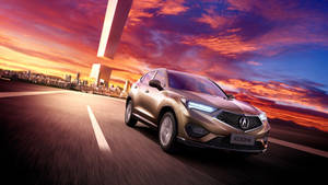 金色Acura CDX SUV在日落高速公路上行駛，背景是城市天際線。