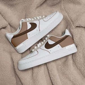 米色抓絨毯上的白色和棕色 Nike Air Force 1 運動鞋，帶有 'KITONY' 品牌標誌。