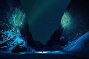 在極光和星空下，雪地山峽中手持電筒的人 — 極光 壁紙
