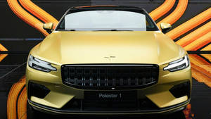 金色Polestar 1電動車的前視圖，背景為橙色電纜。 — 汽車 壁紙