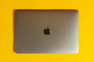 關閉的銀色 MacBook 手提電腦在亮黃色背景上