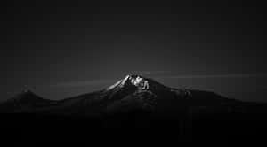 積雪山峰剪影，背景為漸變天空，下方是黑暗的城市景觀。 — 純黑 壁紙