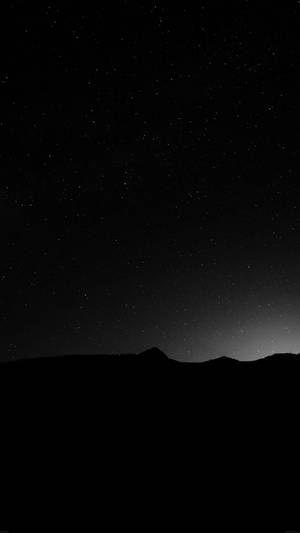 在星空夜空下，山脈輪廓在地平線上有微光。