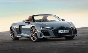 日落時分瀝青路面上的銀色奧迪R8 Spyder開篷車