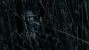 身穿迷彩裝備的士兵在夜間隱藏在高高的蘆葦叢中，手持步槍。 — 軍事動圖 壁紙
