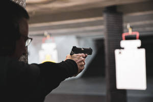 在室內射擊場用手槍瞄準靶子的人士