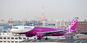 Peach Airlines飛機在城市景觀上空爬升，可見一座塔。