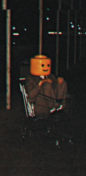 一個有LEGO頭嘅人夜晚喺人造燈光下坐喺輪椅上。