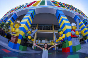興奮的孩子在主題公園的巨型LEGO角色雕像前擺姿勢。