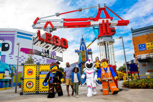 家庭與LEGO Movie角色在主題公園入口散步。