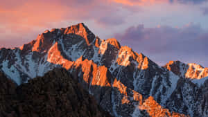 雪山山峰在夕陽下閃耀，天空呈現粉紅色和紫色。 — 冬天桌面 壁紙