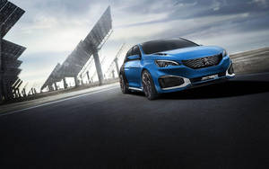 藍色Peugeot 308 GT在黃昏時停放在太陽能板旁邊。