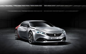 時尚的銀紅色Peugeot Exalt概念車在黑暗的工業車庫中，帶有戲劇性的燈光。