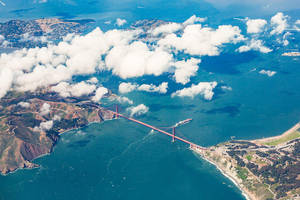 從上方觀看金門大橋，下方有雲朵和海洋 — 加州 壁紙