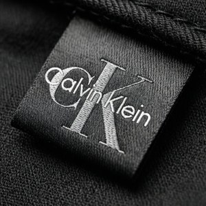 Calvin Klein服裝品牌標籤特寫，黑色布料上有白色縫線。