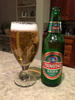 青島啤酒瓶和酒杯在廚房檯面上帶有泡沫