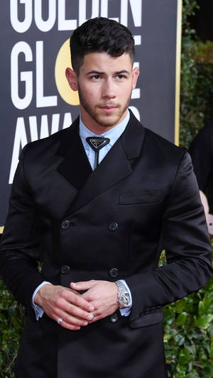 Nick Jonas 在金球獎上穿著黑色西裝，綠色背景。 — 啞光黑色 壁紙