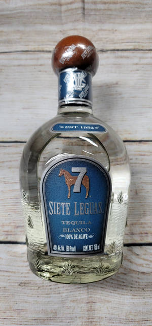 透明tequila瓶，藍色標籤和棕色瓶塞，木質背景。