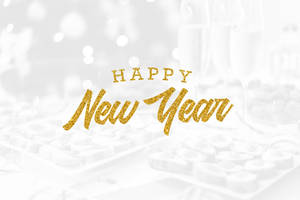 在模糊的香檳和朱古力上以金色閃粉呈現的Happy New Year文字。