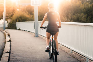 女性在黃金時段日落時騎單車過橋。 — 自行車 壁紙