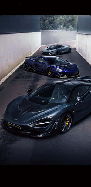 三輛高性能McLaren超級跑車停放在燈光昏暗的混凝土隧道中。 — 黑色動態圖 壁紙