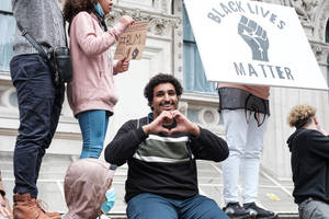 年輕男子在Black Lives Matter抗議活動中微笑並比出心形。 — 情侶擁抱 壁紙
