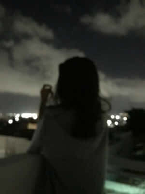夜晚站在屋頂上看著城市燈光的人