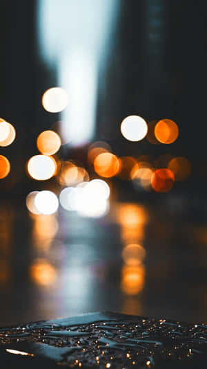 路面上的雨滴反射出夜間閃爍的城市燈光。