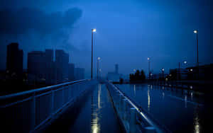 黃昏時分，雨水浸濕的城市橋樑，閃爍的街燈和背景中黑暗的摩天大樓。