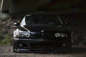 黑色BMW跑車停泊在混凝土天橋下的碎石路上。