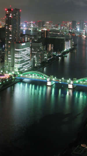 城市夜景，有燈光璀璨的建築物和在水面上發光的橋樑。