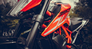一輛鮮橙色KTM 390越野電單車帶有黑色點綴，停放在森林中。