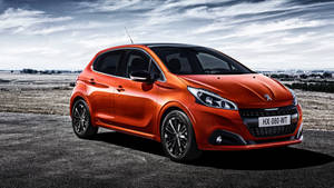 橙色Peugeot 208停泊在瀝青路上，背景為多雲天空。