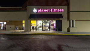 夜間照亮的Planet Fitness健身室入口，外面有濕人行道。