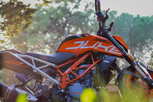 橙色KTM Duke 390電單車在日落時停泊在森林中。