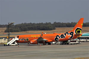 橙色Mango Airlines噴射機停在機場閘口，附有登機梯和地勤人員。