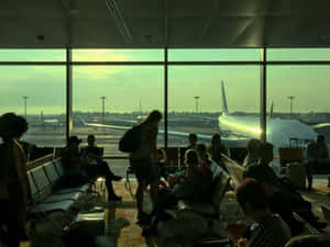 在機場客運大樓內觀看日落時飛機的剪影旅客。