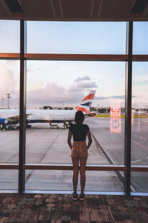 暮色中透過機場窗戶觀看英國航空飛機的人。