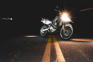 夜間黑暗道路上帶有明亮頭燈的銀色電單車，帶有動態模糊效果。