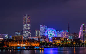 夜間城市天際線，摩天輪和摩天大樓倒映在水中。 — 城市景觀 壁紙