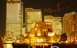 河邊發光的歐式建築，背後有燈光摩天大樓 — 夜景城市 壁紙